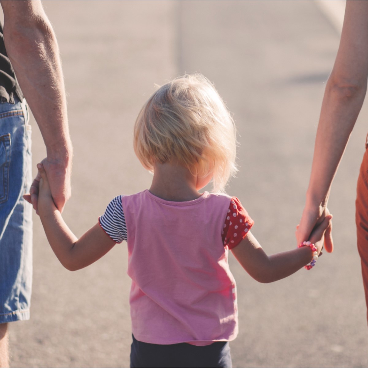 Un jeune enfant tient les mains d'adultes